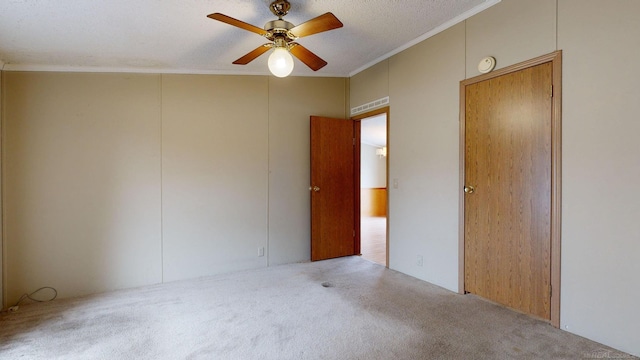 empty room with ceiling fan, light colored carpet, a textured ceiling, and ornamental molding