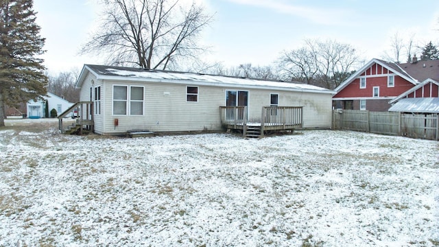 snow covered rear of property with a wooden deck