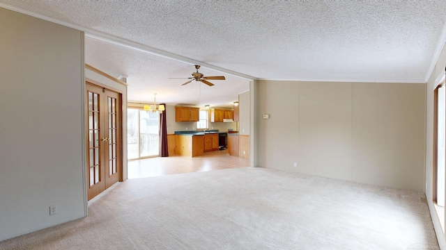 unfurnished living room with french doors, light colored carpet, a textured ceiling, vaulted ceiling, and ceiling fan with notable chandelier