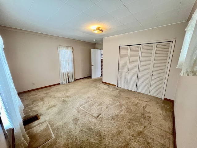 unfurnished bedroom with light carpet and a closet