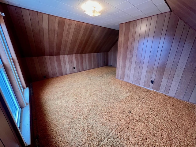 additional living space featuring wood walls, lofted ceiling, and carpet floors