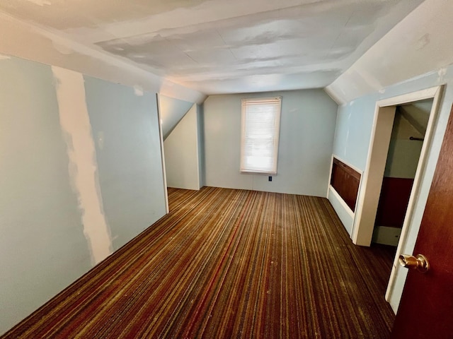 additional living space featuring dark colored carpet and vaulted ceiling