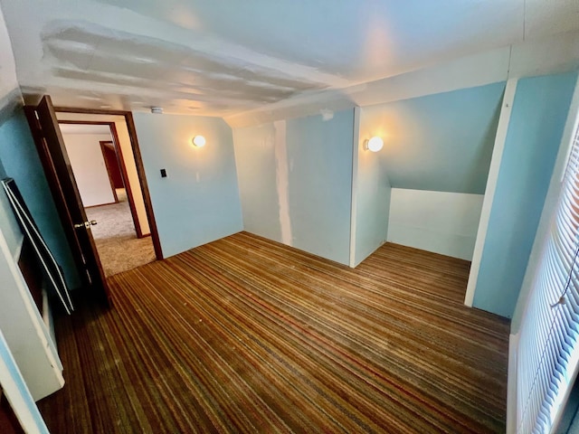 interior space featuring vaulted ceiling and dark colored carpet