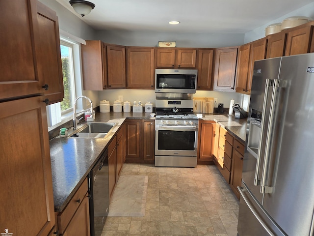 kitchen with stainless steel appliances, dark stone counters, and sink