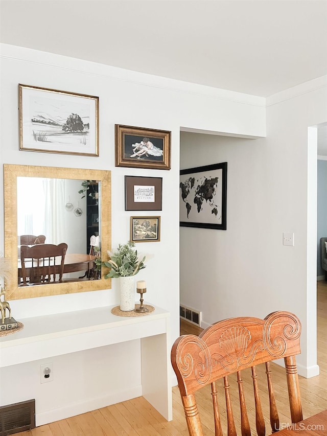 living area with crown molding and light wood-type flooring