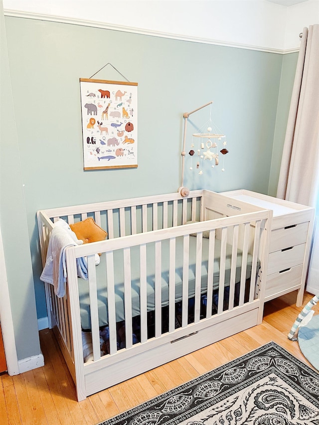 bedroom featuring light hardwood / wood-style flooring and a nursery area