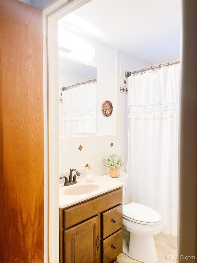 bathroom featuring decorative backsplash, tile patterned floors, vanity, tile walls, and toilet