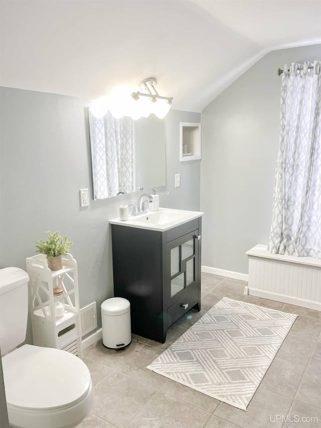 bathroom with toilet, vanity, tile patterned flooring, and vaulted ceiling