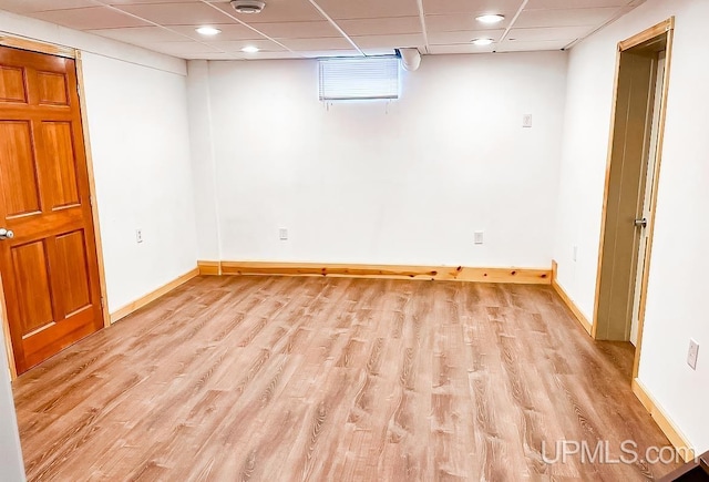 basement featuring light wood-type flooring and a paneled ceiling