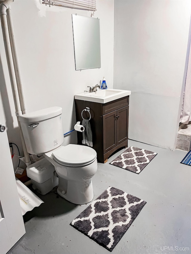 bathroom with vanity, toilet, and concrete floors