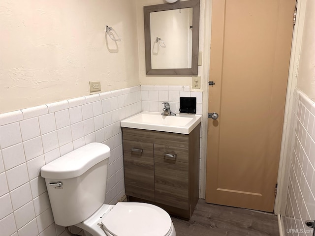 bathroom featuring toilet, vanity, tile walls, and hardwood / wood-style flooring