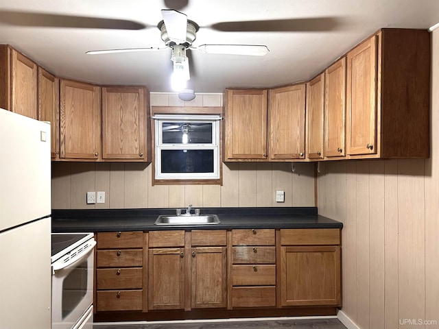 kitchen featuring ceiling fan, sink, range, white fridge, and wood walls