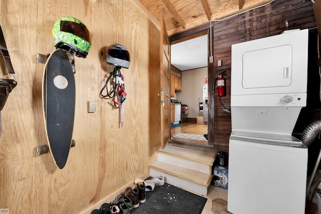 laundry room with stacked washer and clothes dryer and wood walls