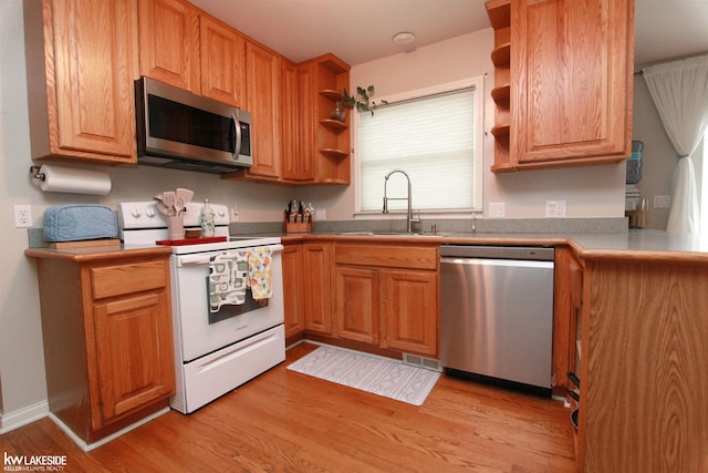 kitchen with stainless steel appliances, light hardwood / wood-style floors, and sink