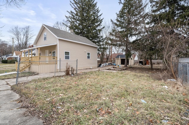 view of side of property with covered porch, a shed, and a lawn