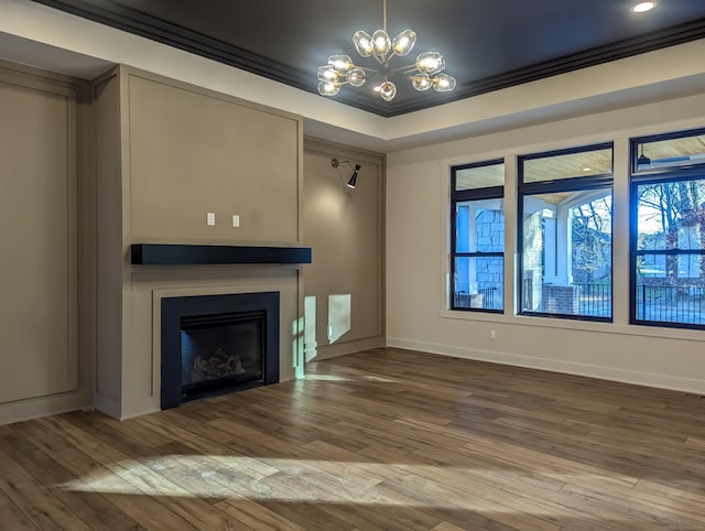 unfurnished living room with a tray ceiling, hardwood / wood-style floors, ornamental molding, and an inviting chandelier