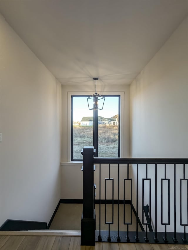 stairway with hardwood / wood-style floors and an inviting chandelier