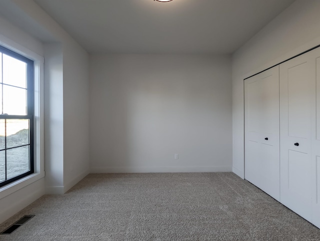 unfurnished bedroom with carpet, a closet, and multiple windows