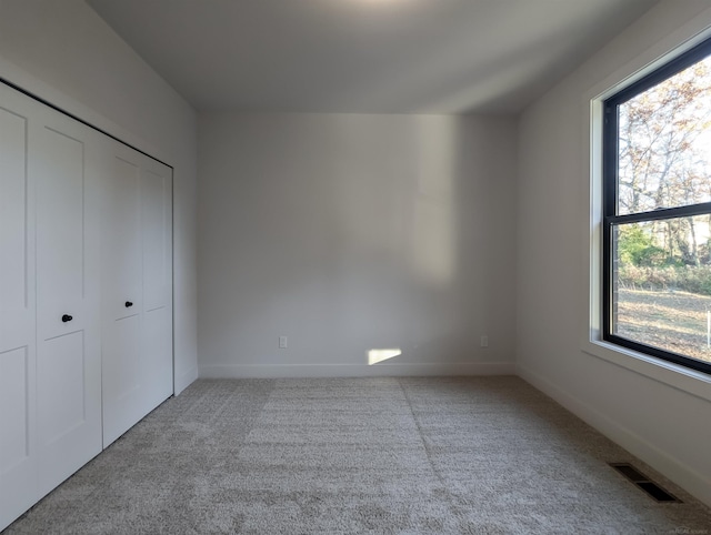 unfurnished bedroom featuring light colored carpet and a closet