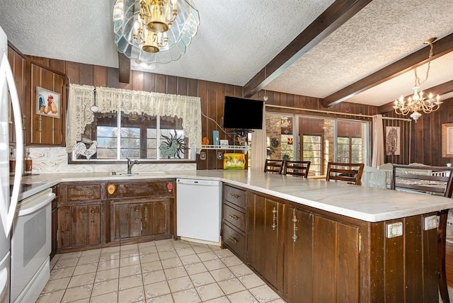 kitchen with dishwasher, sink, beamed ceiling, range, and a chandelier