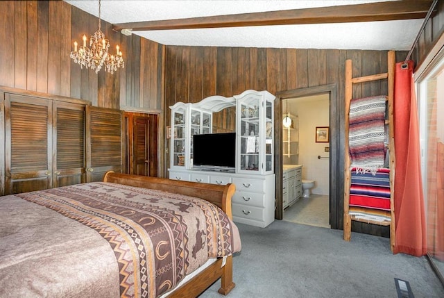 carpeted bedroom with beamed ceiling, a chandelier, wooden walls, and ensuite bathroom