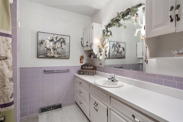 bathroom featuring tile walls, tile patterned flooring, vanity, and a textured ceiling