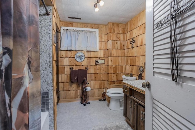 bathroom with wooden walls, vanity, and toilet