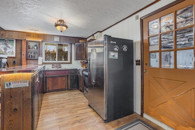 kitchen with appliances with stainless steel finishes, a textured ceiling, and wooden walls