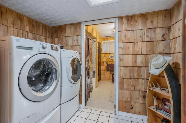 laundry area featuring light tile patterned flooring, independent washer and dryer, and wood walls