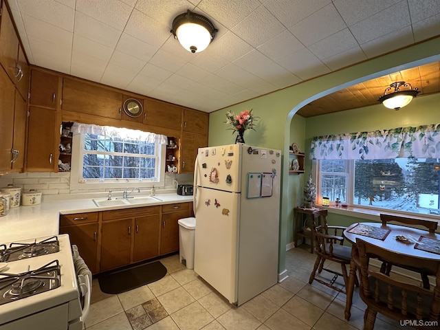 kitchen featuring plenty of natural light, white appliances, sink, and light tile patterned floors