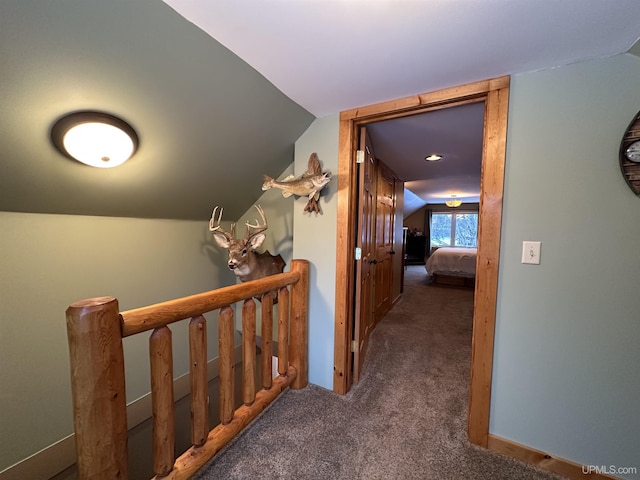 corridor with dark carpet and lofted ceiling