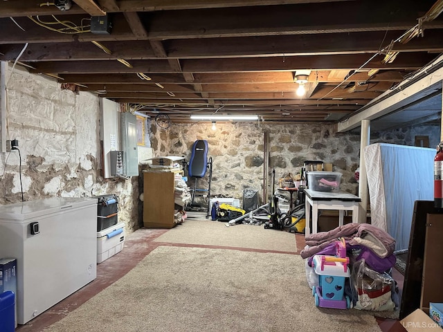 basement featuring electric panel and fridge