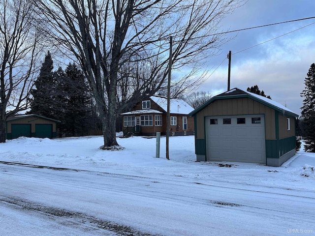 yard layered in snow featuring a garage and an outdoor structure