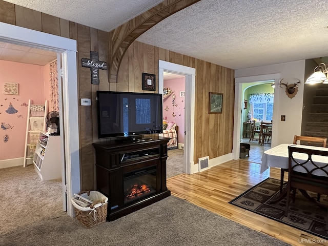 living room featuring carpet flooring, a textured ceiling, and wooden walls