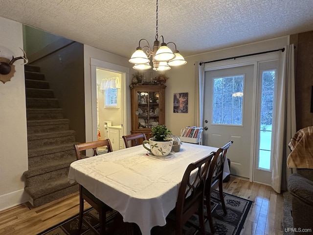 dining area featuring hardwood / wood-style flooring, a textured ceiling, and an inviting chandelier