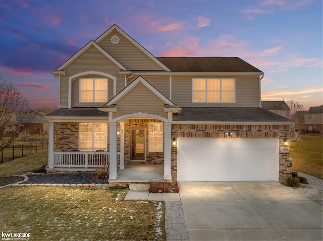 view of front of property featuring covered porch, a garage, and a lawn