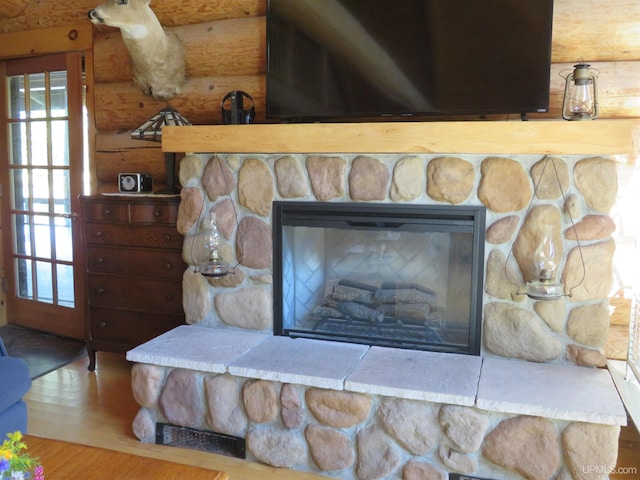 interior details featuring a stone fireplace, wood-type flooring, and log walls