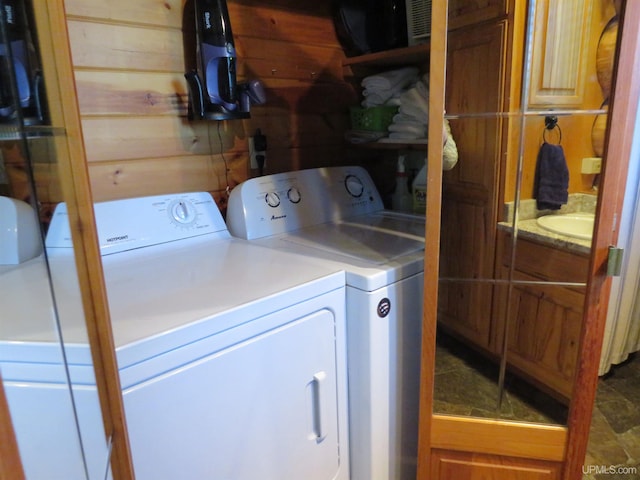 washroom featuring wooden walls, sink, and independent washer and dryer