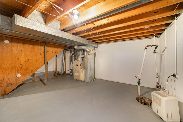 basement with gas water heater, heating unit, and wood walls