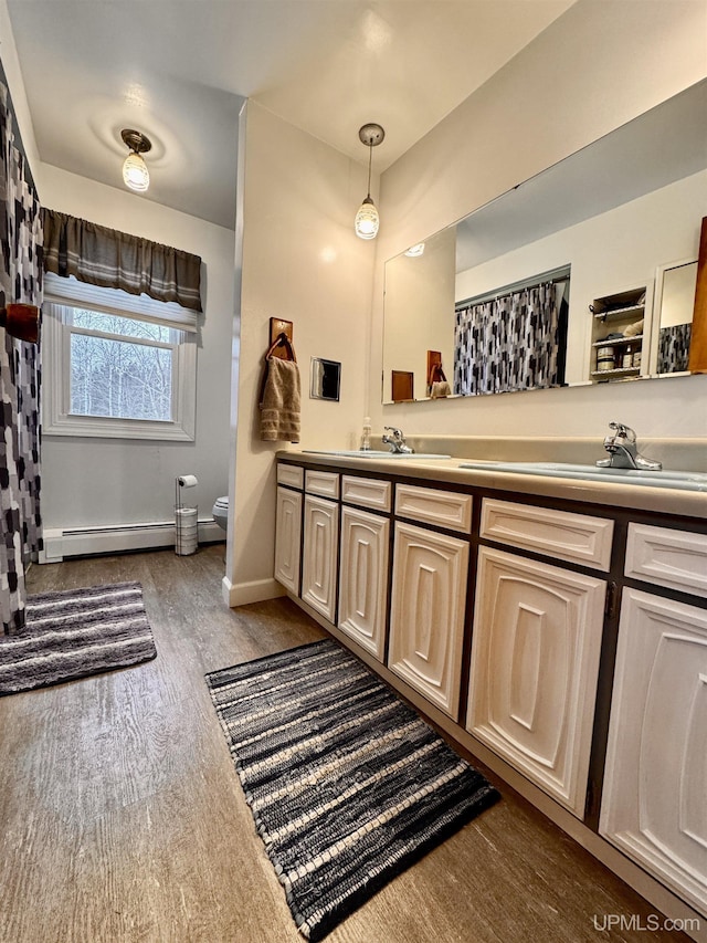 bathroom featuring hardwood / wood-style floors, vanity, toilet, and a baseboard heating unit