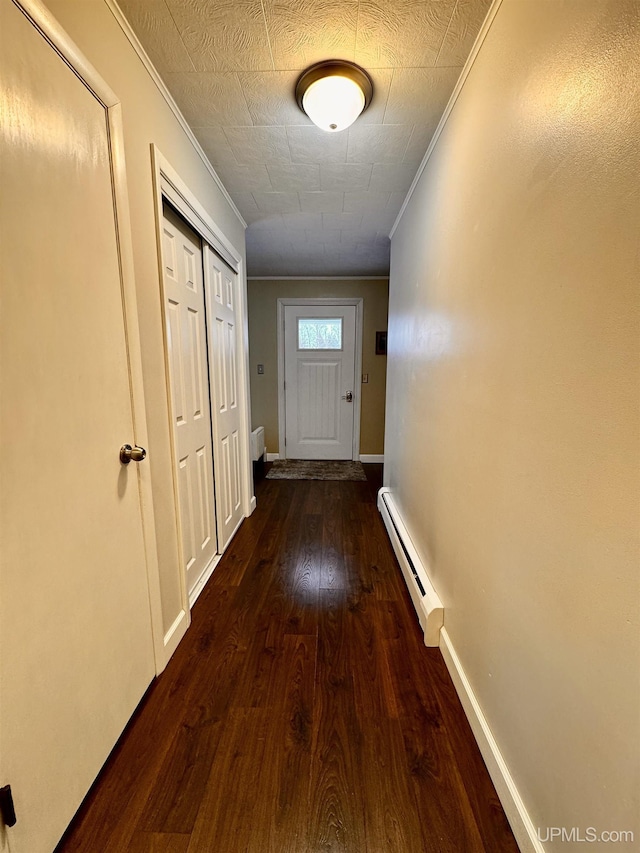 hall with dark hardwood / wood-style floors, crown molding, and a baseboard heating unit