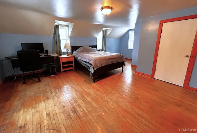 bedroom with light wood-type flooring and vaulted ceiling