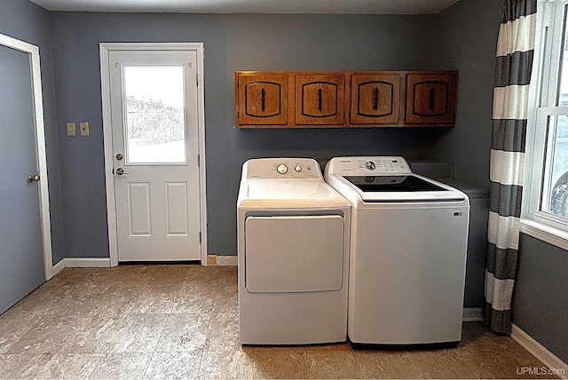 clothes washing area featuring washer and dryer and cabinets