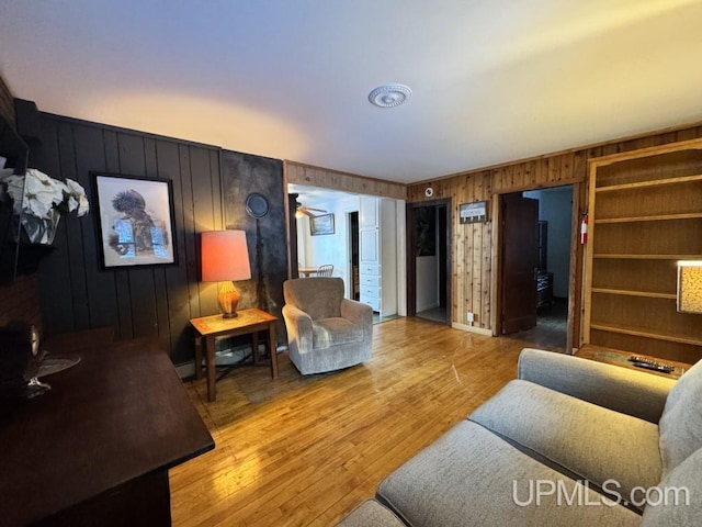 living room featuring hardwood / wood-style flooring, ceiling fan, and wooden walls