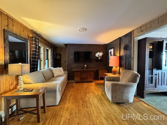 living room with wood walls, light wood-type flooring, and a baseboard radiator