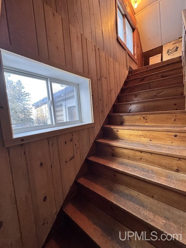 stairway featuring wood walls and a healthy amount of sunlight