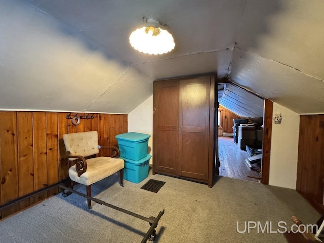 additional living space with wood walls, light colored carpet, and vaulted ceiling