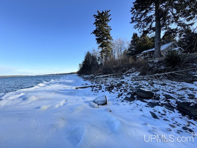 yard layered in snow featuring a water view