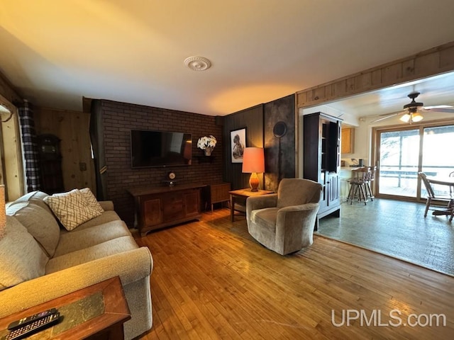 living room with wood-type flooring, ceiling fan, and wood walls