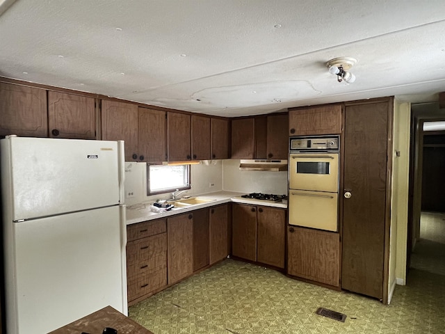 kitchen with dark brown cabinets, white appliances, and sink